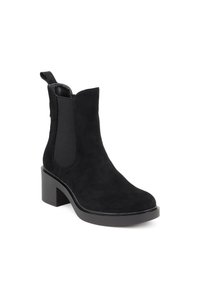 Stivale alla caviglia in suede nero con pannelli laterali elasticizzati, punta rotonda e tacco spesso. Presenta un tab per una facile calzata. Texture liscia.