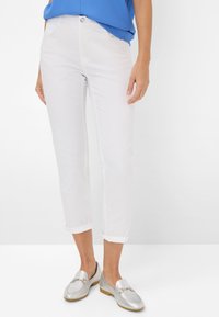 Weiße, kurze Hosen aus leichtem Stoff, mit umgeschlagenen Säumen und schmalem Schnitt, kombiniert mit silbernen Slippern und einem blauen Oberteil.