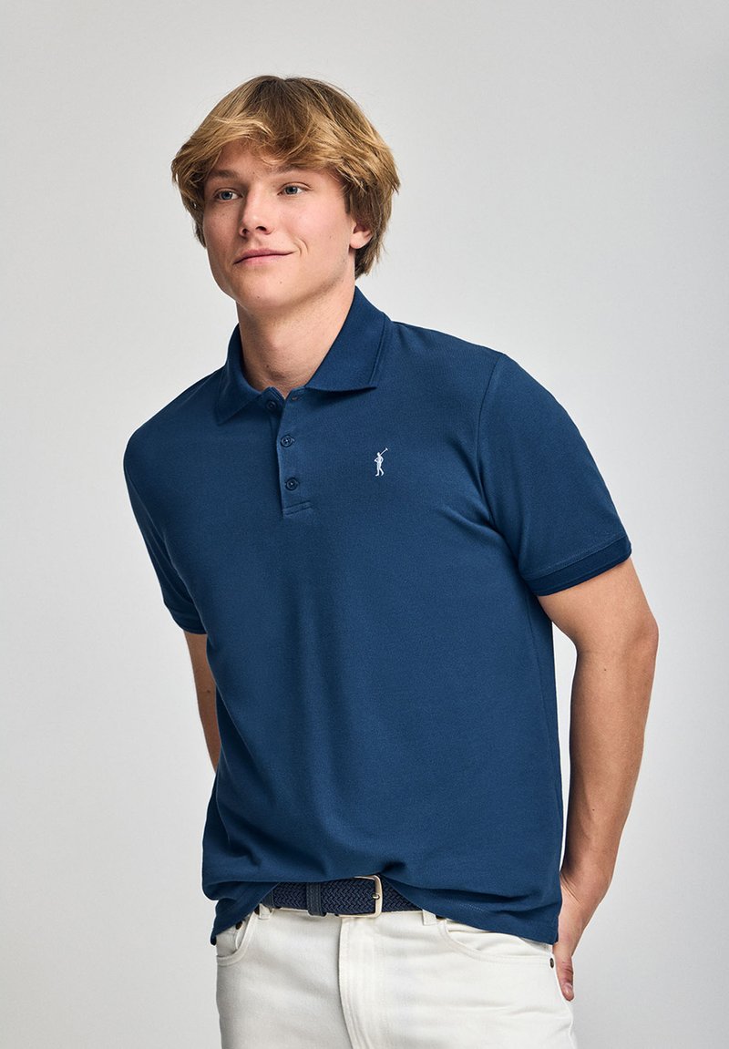 Dunkelblaues Poloshirt mit Drei-Knopf-Leiste, kurzen Ärmeln und gesticktem Logo auf der Brust. Baumwollmaterial mit glatter Textur.