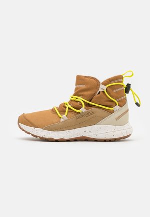 Bruine waterdichte Merrell wandellaars met gele veters, wit gespikkelde zool en trekkoord aan de achterkant, ontworpen voor gebruik buitenshuis.