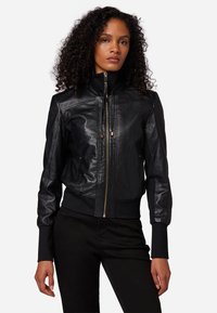Giacca bomber in pelle nera con chiusura a zip, polsi e colletto a coste. Presenta un design aderente e una texture liscia.