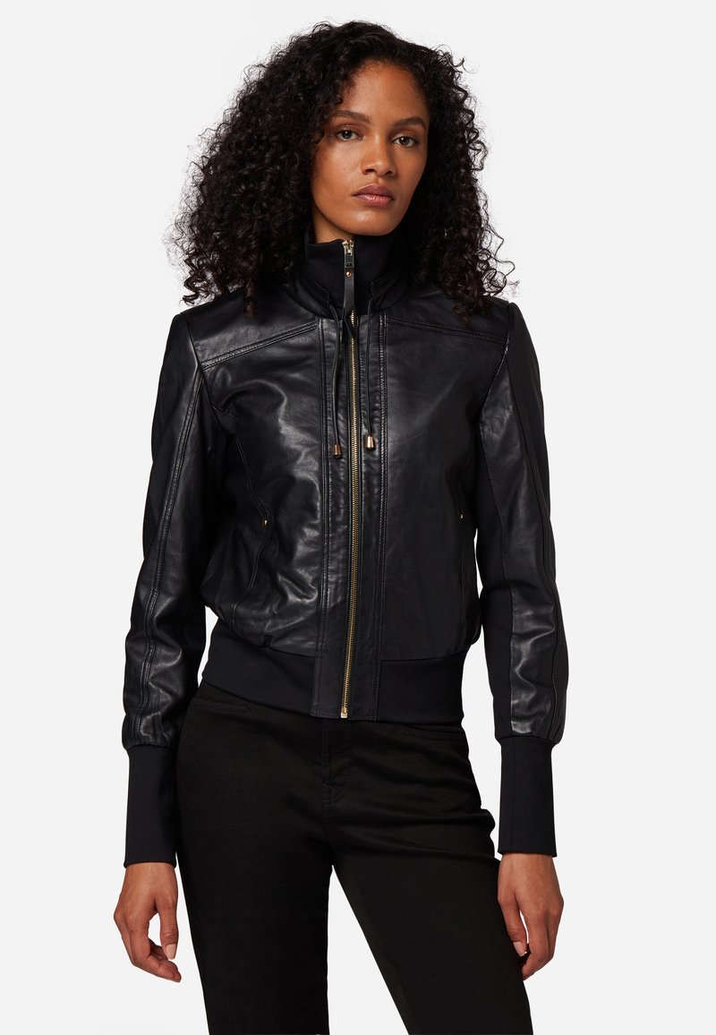 Giacca bomber in pelle nera con chiusura a zip, polsi e colletto a coste. Presenta un design aderente e una texture liscia.