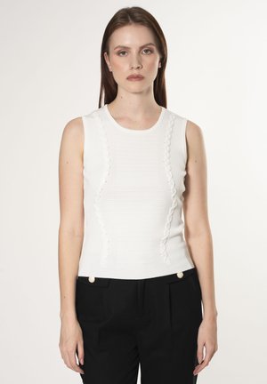 Top bianco senza maniche con accenti ondulati testurizzati sui lati, caratterizzato da un collo rotondo e un design aderente. Abbinato a pantaloni neri.