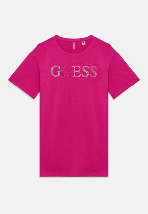 T-shirt rose vif à manches courtes avec un col rond et le mot « GUESS » écrit en strass multicolores sur la poitrine.