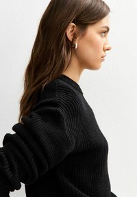 Maglione nero lavorato a maglia con un motivo testurizzato, dotato di maniche lunghe leggermente arricciate e un colletto a costine.