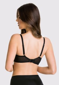 Czarny koronkowy stanik z regulowanymi ramiączkami, przezroczystą tylną częścią oraz delikatnym falbanym wykończeniem na obwodzie. Proste zapięcie na haczyk.