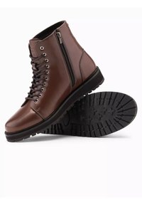 Brune læder ankle boots med snørebånd foran, lynlås i siden, rund tå og en struktureret sort gummisål med træk mønstre.