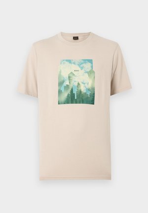 Beige bomulls-t-shirt med ett grönt och blått grafiskt tryck av träd mot en molnig himmel. "BOSS" är tryckt i mitten av motivet.