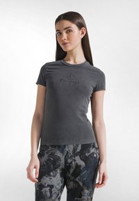 Grå t-shirt med korta ärmar och rund halsringning, med tryckt "Re-Pose"-design på framsidan. Tillverkad av mjukt tyg med en figurnära passform.