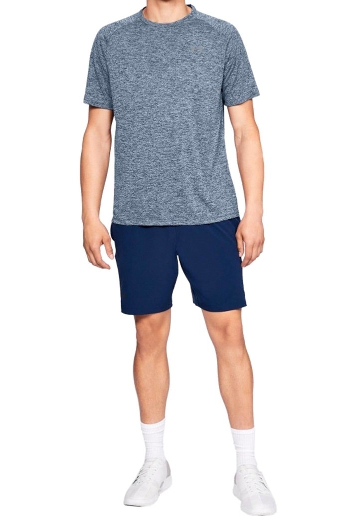 Granatowe spodenki o luźnym kroju w połączeniu z melanżowym szarym, sportowym t-shirtem z krótkim rękawem, wykonanym z lekkiego materiału. Białe tenisówki i skarpetki.