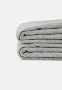 Coperta grigia in lana, piegata ordinatamente, con una consistenza morbida e un colore uniforme, che mostra un design semplice e funzionale.