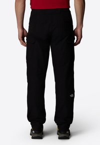 Black cargo pants made of durable fabric with side pockets, featuring a straight leg design and a small logo detail near the hem.
