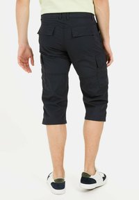 Knee-length, navy cargo shorts with a smooth texture, featuring back pockets and a straight cut, paired with white sneakers.