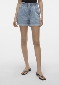 Ljusblå denimshorts med uppvikta kanter, elastisk midja, två framfickor och en avslappnad passform. Tillsammans med svarta flip-flopsandaler.