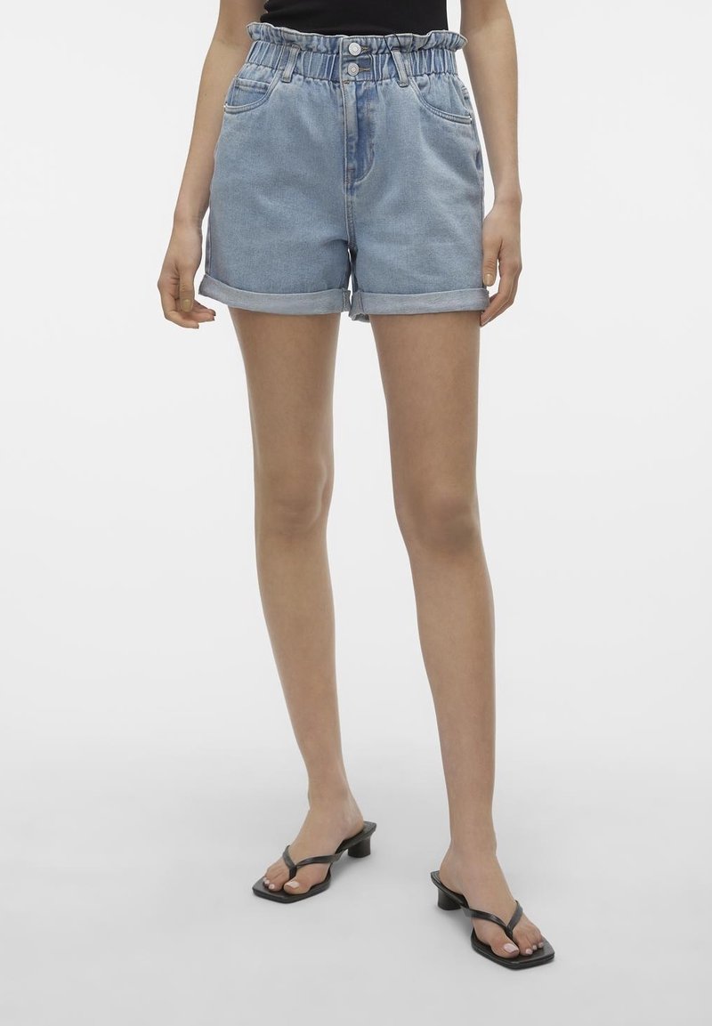 Ljusblå denimshorts med uppvikta kanter, elastisk midja, två framfickor och en avslappnad passform. Tillsammans med svarta flip-flopsandaler.