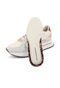 Zapatilla gris claro con acentos dorados, ante beige y una suela negra texturizada. Presenta una plantilla con patrón de leopardo.