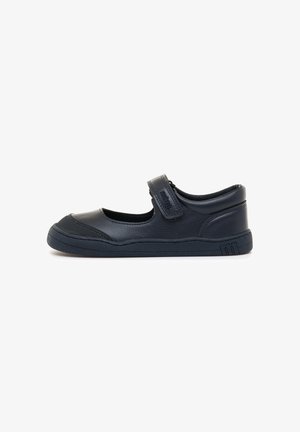 Zapato Mary Jane de cuero negro con puntera redonda, acentos texturizados, correa de velcro ajustable y suela de goma. Diseño sencillo y de perfil bajo.