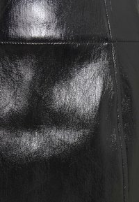 Black faux leather fabric with a glossy, textured surface and visible seam detail, highlighting smooth and shiny finish.