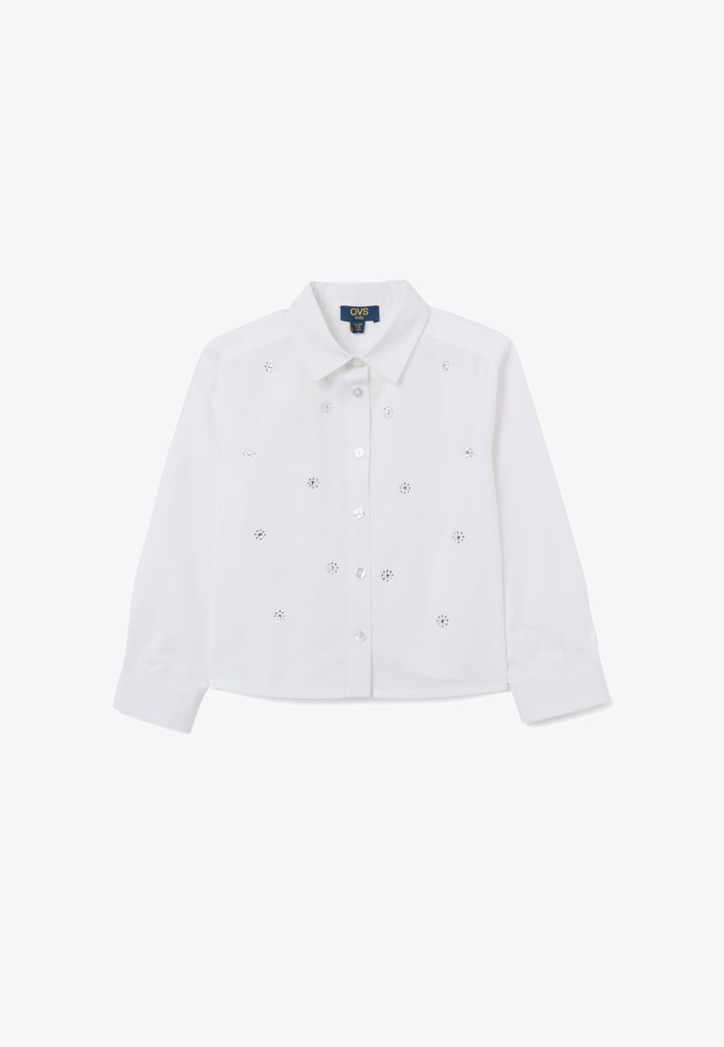 Camicia bianca in cotone a maniche lunghe con colletto bottone, caratterizzata da eleganti motivi a occhiello e piccoli bottoni lungo la parte anteriore.