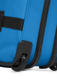 Blauer Koffer mit Rädern, strukturiertem Stoffoberfläche, schwarzen glatten Akzenten und Doppelrädern für Stabilität. Verfügt über einen schwarzen Gurt zur einfachen Handhabung.