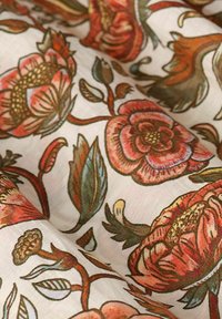 Bunt blühender Stoff mit großen rosa und roten Blumen sowie grünen Blättern auf cremefarbenem Hintergrund; weiche Textur und leichtes Design.