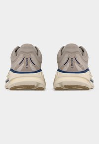 Ζευγάρι μπεζ και ναυτικών τρεξίματος παπουτσιών, εμφανιζόμενα από πίσω, με την επωνυμία "BONDI 9" και χονδρά λευκά πέλματα με ταμπά σόλα.