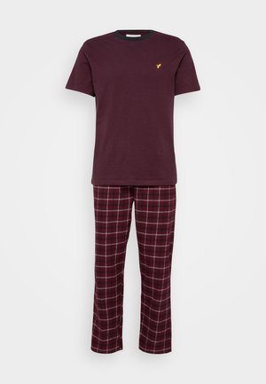 Camiseta marrom de mangas curtas com um logótipo amarelo, combinada com calças de pijama xadrez em tons de marrom, branco e azul escuro. Tecido suave.