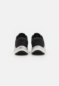 Schwarze Sportschuhe mit einem Mesh-Obermaterial, gepolstertem Schaft und reflektierender weißer Zwischensohle. Mit einer strukturierten schwarzen Gummisohle für Grip.