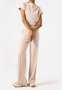 Beige stickad tvådelat set med en kortärmad topp och vida byxor; texturerad tyg; sportiga sneakers med en vågig sula.