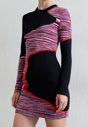 Robe longue ajustée à manches longues avec des rayures horizontales noires et multicolores, comportant des panneaux noirs aux bords rouges irréguliers sur le corps et les manches.