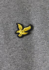 Felpa in tessuto grigio con logo ricamato di un uccello giallo con contorno nero. La texture appare morbida e leggermente mélange.