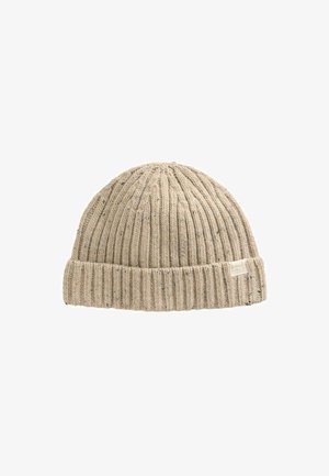 Bonnet beige en maille côtelée avec revers plié et petite étiquette en tissu sur le côté, sur fond blanc.