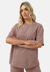 Korte mouw, losvallende top in een stofroze kleur, gemaakt van zachte stof met een ronde hals en subtiele stiksels.