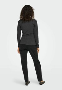 Donkergrijze longsleeve shirt in combinatie met zwarte recht gesneden jeans. Zwarte schoenen met zilveren studs. Glad materiaal, casual pasvorm.