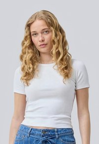 T-shirt branco de manga curta canelada com um design ajustado, combinado com jeans de cintura alta azuis. Tecido texturizado, estilo minimalista.