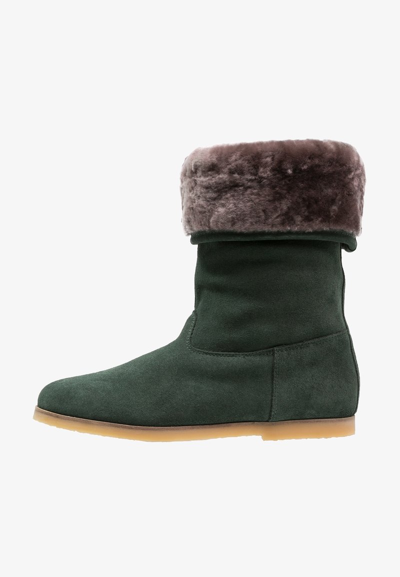 Botte de cheville en daim vert avec un revers en fausse fourrure marron, bout arrondi et semelle en caoutchouc plate. Texture lisse, design minimaliste et sans fermetures visibles.