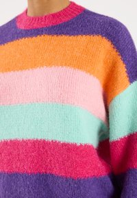 Colorful striped sweater featuring pink, orange, mint green, purple, and red hues. Made of soft, textured fabric with a ribbed neckline.