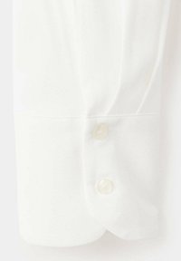 Poignet de chemise blanche avec deux petits boutons ronds blancs et coutures visibles sur un tissu doux.