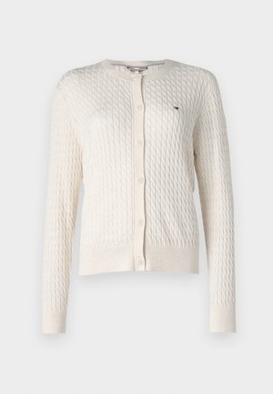 Krämfärgad cardigan med en strukturerad kabelstickning, långa ärmar, rund halsringning och knappstängning. Har en liten logotyp.