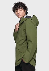 Grüne wasserfeste Jacke mit Kapuze, ausgestattet mit einem Frontreißverschluss und seitlichen Taschen. Hergestellt aus glattem, strapazierfähigem Material mit einer strukturierten Passform.