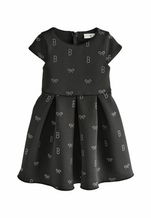 Robe noire à manches courtes, jupe plissée, avec des motifs de nœud de couleur claire et de la lettre 'B'. Fabriquée dans un tissu lisse et structuré.