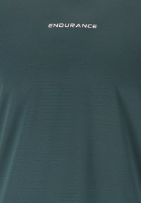 Dunkelgrünes Sportshirt mit dezentem Strukturmuster, ausgestattet mit einem weißen "ENDURANCE"-Logo auf der Brust. Glatte Stoffoberfläche.