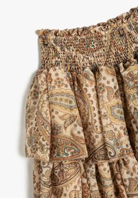 Gonna smockata realizzata in un tessuto beige con un motivo paisley nei toni di blu e arancione. L'orlo arricciato e la superficie texturizzata aumentano l'interesse visivo.