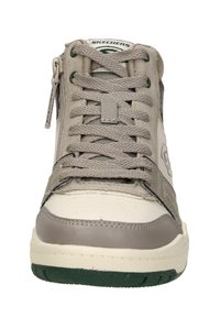 Beige high-top sneaker with lace-up design, leather and suede materials, rubber sole, green accents, and textured panels on sides.