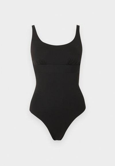 Μαύρο ολόσωμο μαγιό με φαρδιές τιράντες και σχεδιασμό που τονίζει τη μέση, σε απλό φωτεινό φόντο.