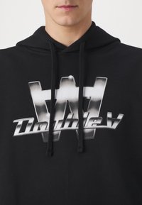 Zwarte hoodie met een groot zilverkleurig grafisch logo met de letter "W" en de tekst "Double V" gecentreerd op de borst. Katoenen stof, casual ontwerp.