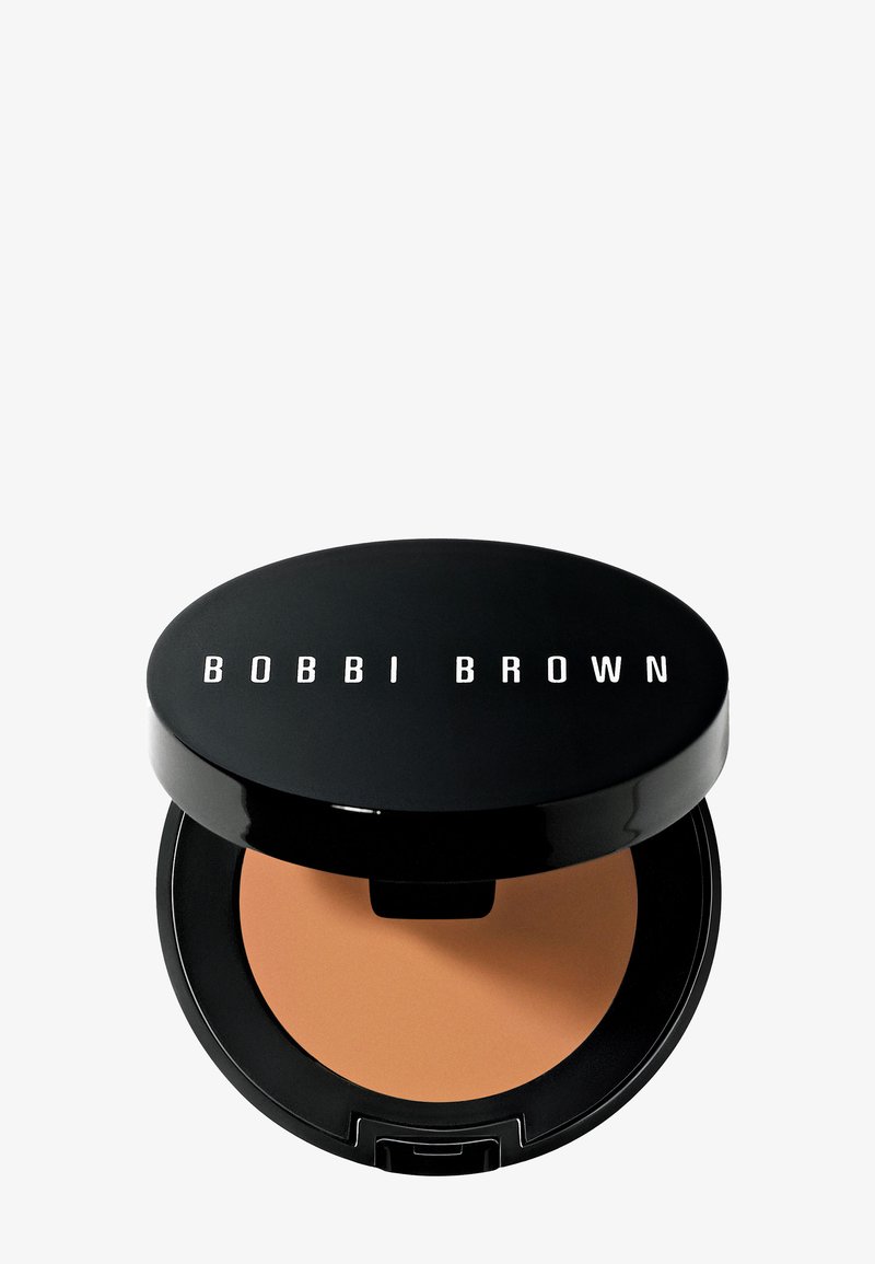 Kompaktpuder in schwarzer Verpackung mit einer glatten, warmen braunen Oberfläche. Das Logo "BOBBI BROWN" ist prominent auf dem Deckel zu sehen.