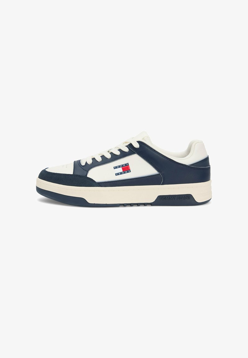Baskets basses blanches et bleu marine avec fermeture à lacets, semelle en caoutchouc, et logo Tommy Jeans sur le côté et la semelle intermédiaire.