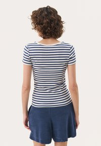 Haut à manches courtes à rayures bleu marine et blanches, texture côtelée, col rond, associé à un short bleu marine, montrant un tissu lisse et une coupe décontractée.