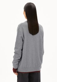 Gray sweatshirt with a relaxed fit, ribbed cuffs and hem, and a soft texture. Layered over a maroon shirt underneath.